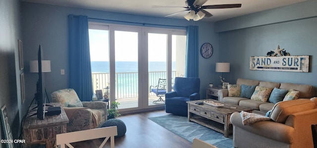 living room featuring ceiling fan, a water view, a healthy amount of sunlight, and hardwood / wood-style flooring