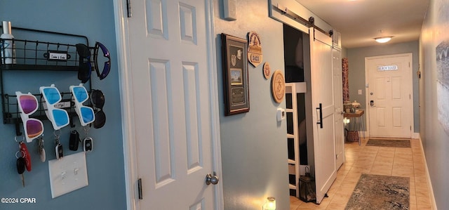 hallway featuring a barn door and light tile patterned floors