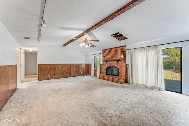 unfurnished living room with vaulted ceiling with beams, a brick fireplace, ceiling fan, and wooden walls