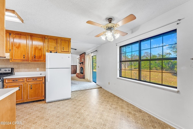 kitchen with ceiling fan, white refrigerator, a healthy amount of sunlight, and stainless steel range