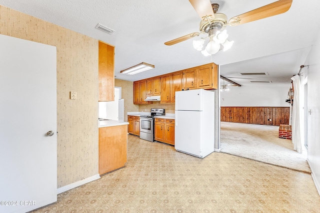 kitchen featuring a textured ceiling, ceiling fan, electric range, white fridge, and wood walls