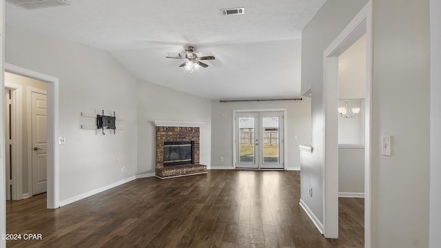 unfurnished living room featuring french doors, ceiling fan with notable chandelier, vaulted ceiling, dark hardwood / wood-style floors, and a fireplace