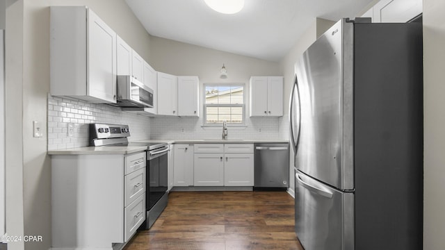 kitchen featuring appliances with stainless steel finishes, backsplash, sink, white cabinetry, and lofted ceiling