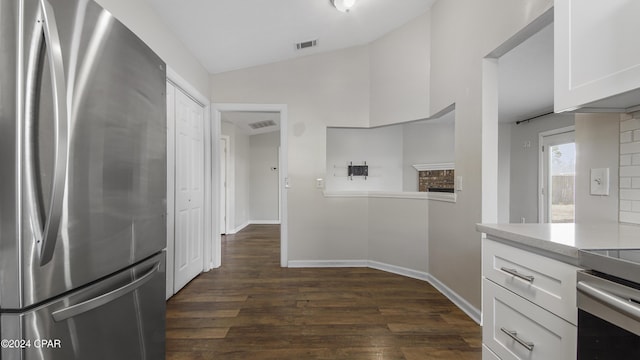 kitchen with stainless steel fridge, backsplash, dark wood-type flooring, white cabinets, and lofted ceiling