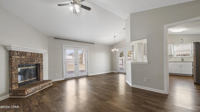 unfurnished living room with a fireplace, french doors, ceiling fan with notable chandelier, and lofted ceiling