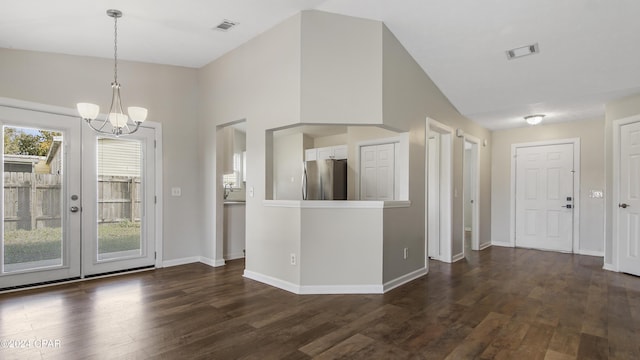 interior space with pendant lighting, dark wood-type flooring, an inviting chandelier, vaulted ceiling, and stainless steel refrigerator