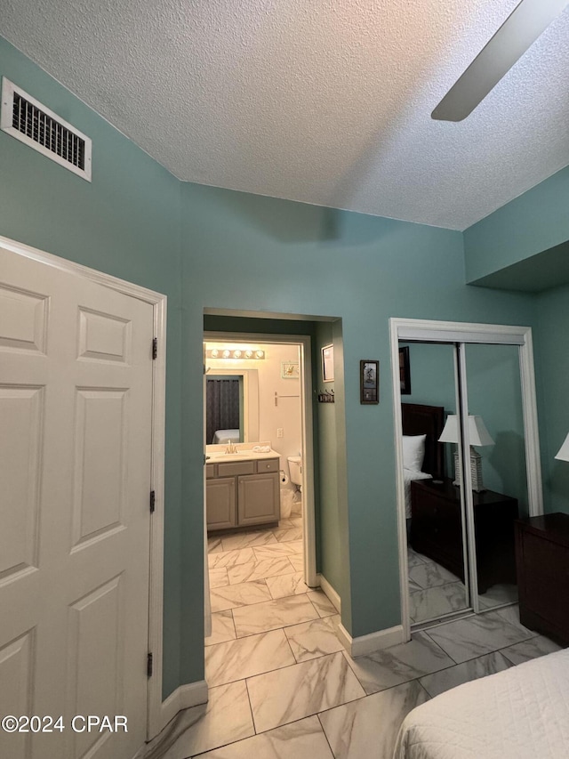 bedroom featuring a textured ceiling, ceiling fan, sink, and a closet