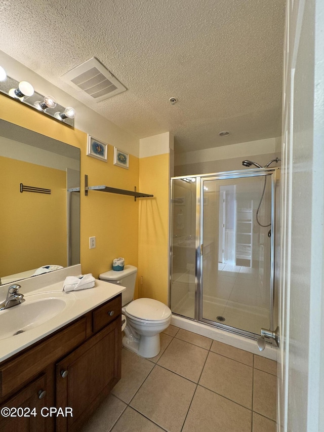 bathroom featuring tile patterned floors, vanity, a shower with shower door, and toilet