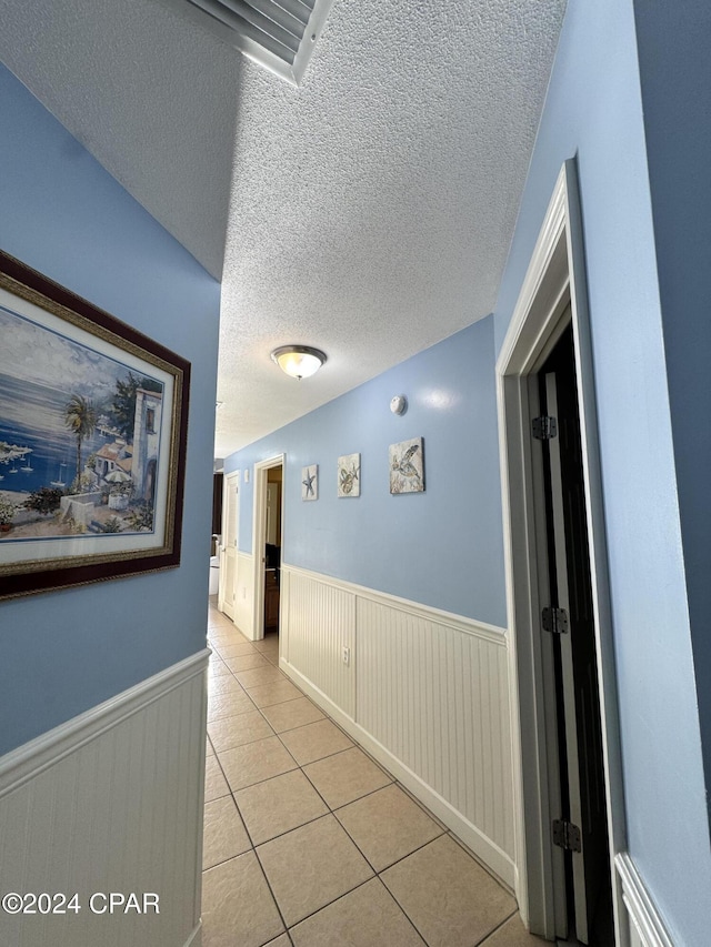 hallway with light tile patterned floors and a textured ceiling