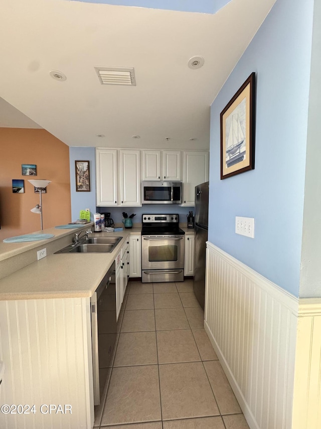 kitchen with black appliances, white cabinets, sink, light tile patterned flooring, and kitchen peninsula