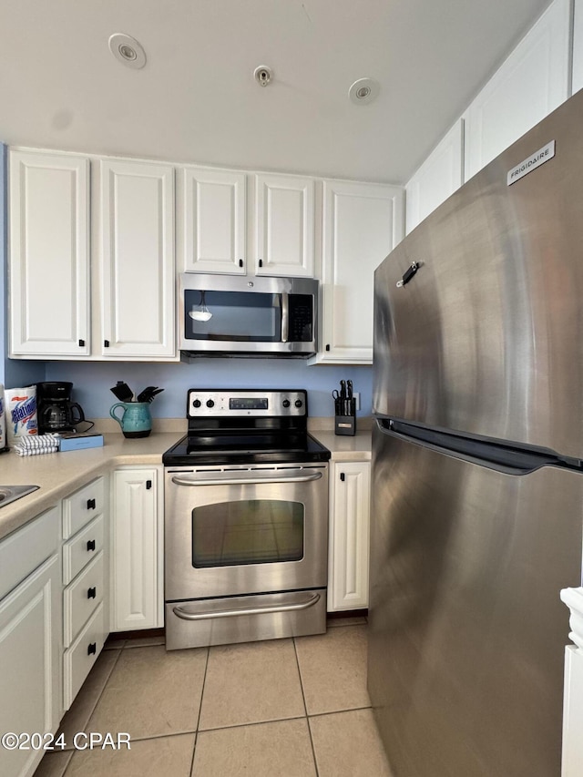 kitchen featuring stainless steel appliances, white cabinetry, and light tile patterned flooring