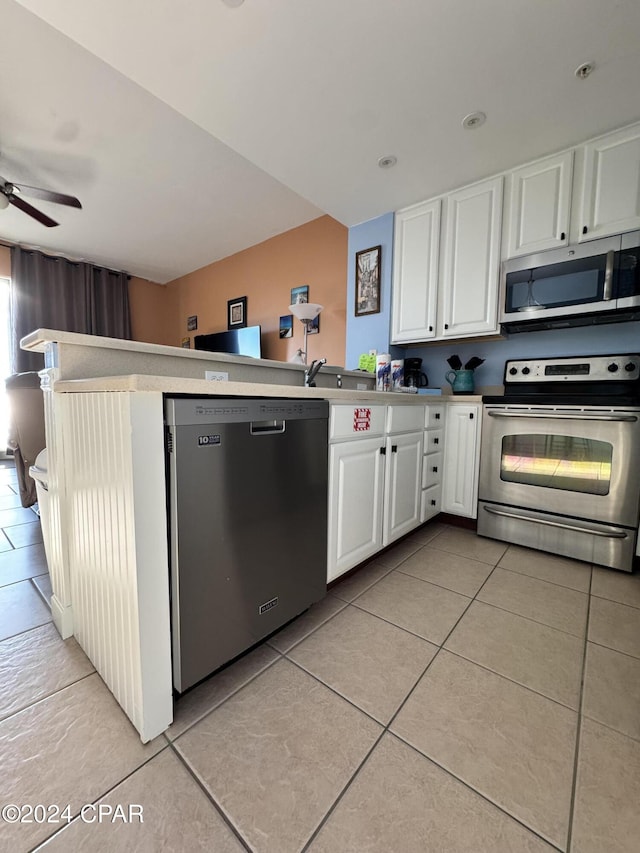 kitchen with kitchen peninsula, appliances with stainless steel finishes, ceiling fan, light tile patterned floors, and white cabinets