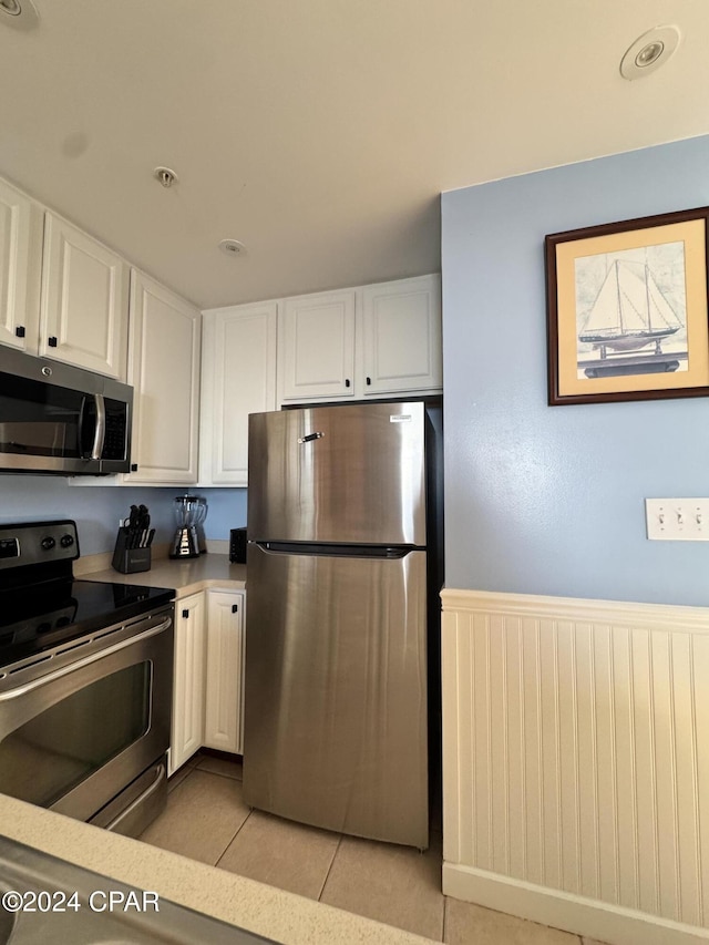 kitchen with white cabinets, light tile patterned floors, and stainless steel appliances