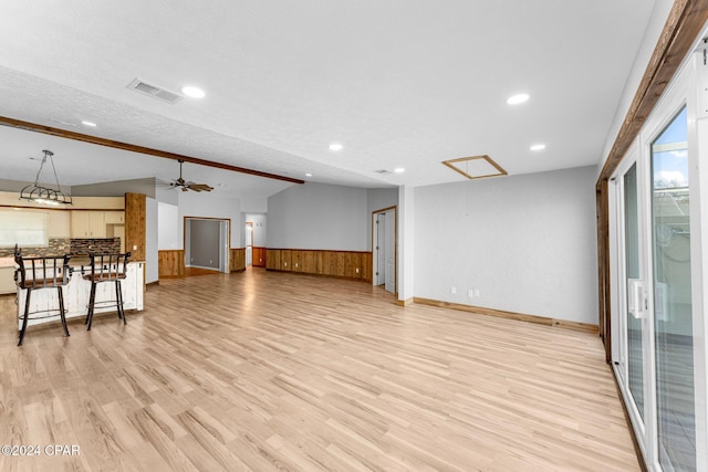 living room with a textured ceiling, light wood-type flooring, vaulted ceiling, and ceiling fan