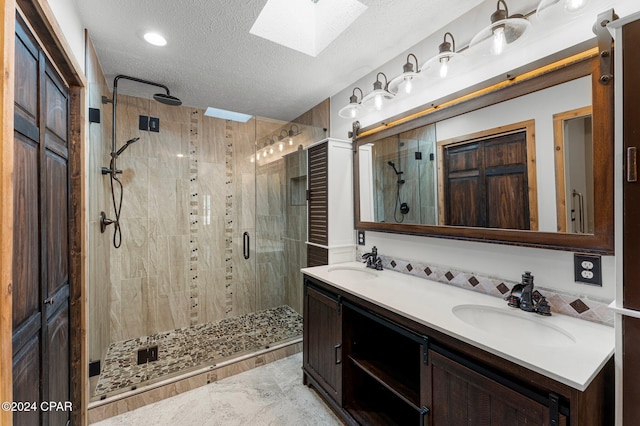 bathroom featuring a skylight, a shower with door, vanity, and a textured ceiling