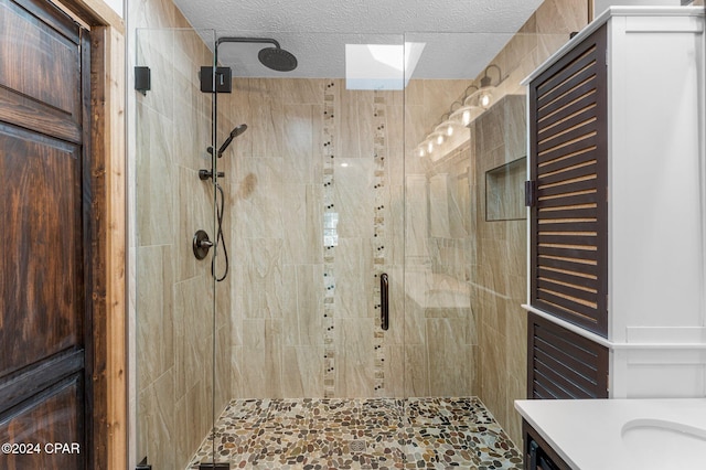 bathroom featuring vanity, a shower with shower door, and a textured ceiling