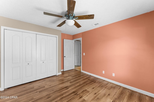 unfurnished bedroom with hardwood / wood-style floors, a textured ceiling, a closet, and ceiling fan