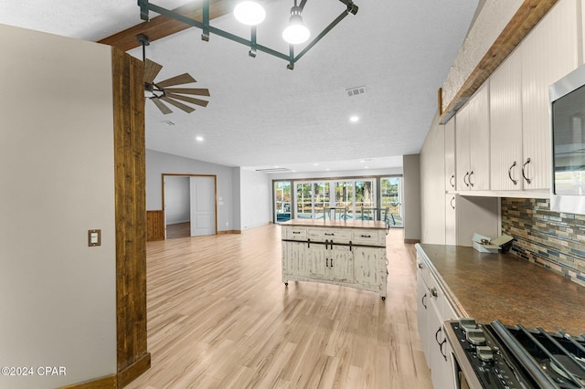 kitchen with white cabinets, a textured ceiling, appliances with stainless steel finishes, tasteful backsplash, and light hardwood / wood-style floors