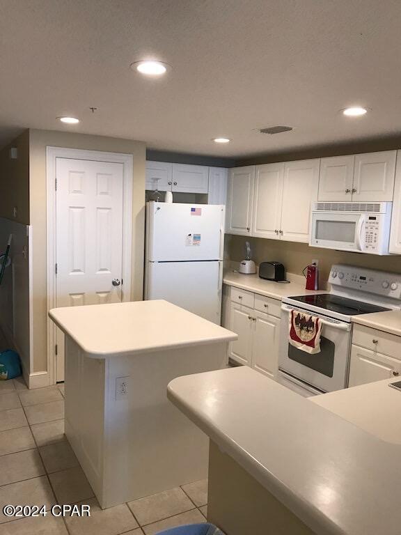 kitchen with white cabinetry, light tile patterned flooring, and white appliances