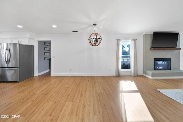 unfurnished living room featuring a notable chandelier and light hardwood / wood-style flooring