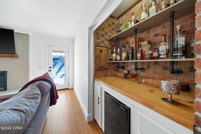 bar featuring white cabinets, light wood-type flooring, fridge, and wood counters