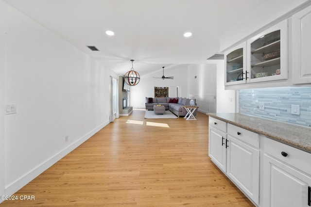 kitchen with backsplash, ceiling fan, decorative light fixtures, white cabinets, and light hardwood / wood-style floors