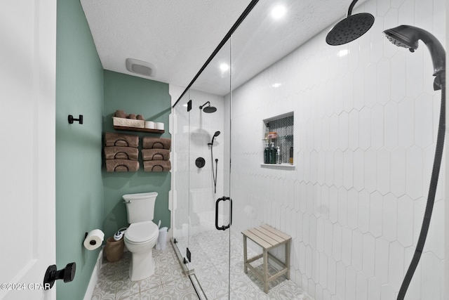 bathroom featuring tile patterned flooring, a shower with shower door, a textured ceiling, and toilet