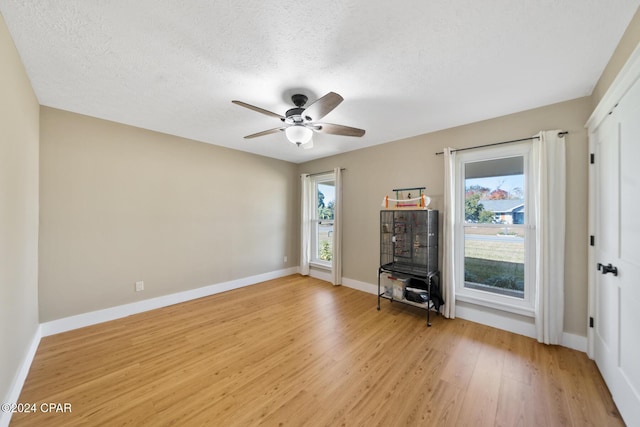 interior space with a wealth of natural light, ceiling fan, a textured ceiling, and light wood-type flooring