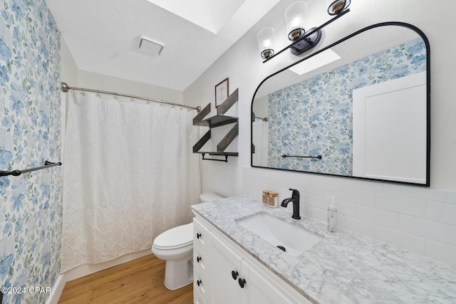 bathroom with tasteful backsplash, vanity, a textured ceiling, hardwood / wood-style floors, and toilet