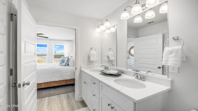 ensuite bathroom with a sink, visible vents, wood finished floors, and ensuite bath