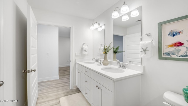 full bath with a sink, toilet, wood finished floors, and double vanity