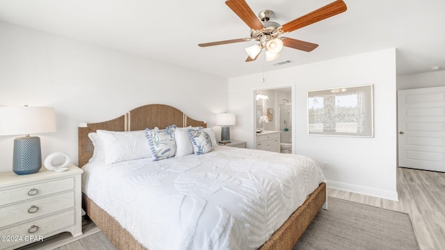 bedroom featuring a ceiling fan, visible vents, baseboards, ensuite bath, and light wood-style floors