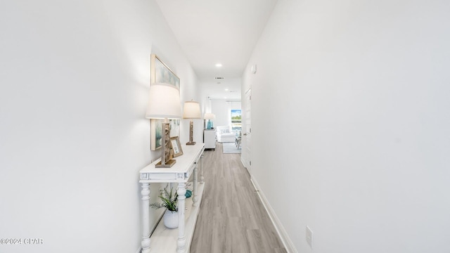 hallway featuring recessed lighting, baseboards, and light wood-style flooring