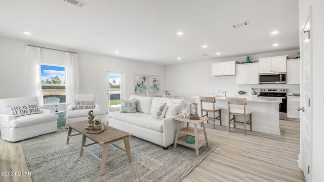 living area with recessed lighting, visible vents, and light wood finished floors