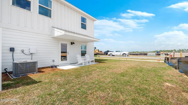 rear view of house featuring a lawn, board and batten siding, and central AC