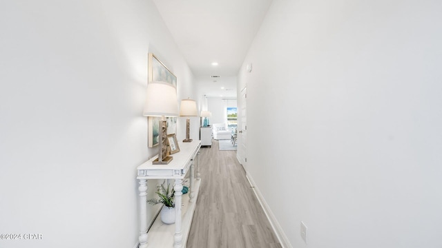 hall featuring light wood-style flooring, recessed lighting, and baseboards