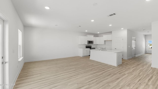 kitchen featuring visible vents, open floor plan, light wood-style flooring, appliances with stainless steel finishes, and a sink