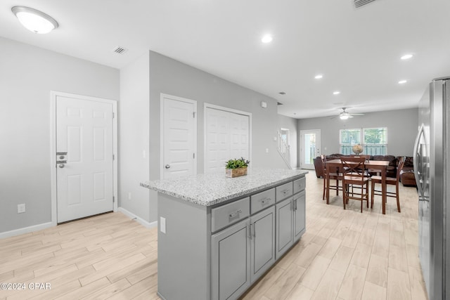 kitchen featuring light wood finished floors, a kitchen island, visible vents, and freestanding refrigerator