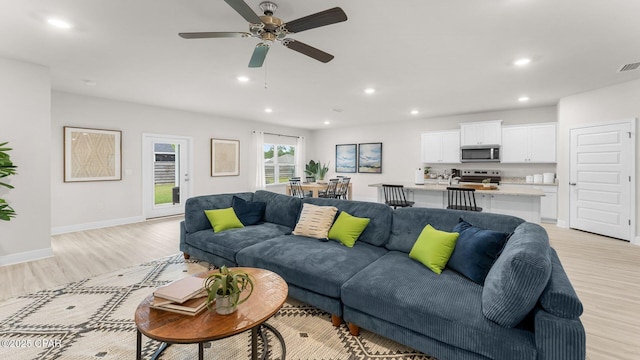 living area with visible vents, light wood-style flooring, a ceiling fan, recessed lighting, and baseboards