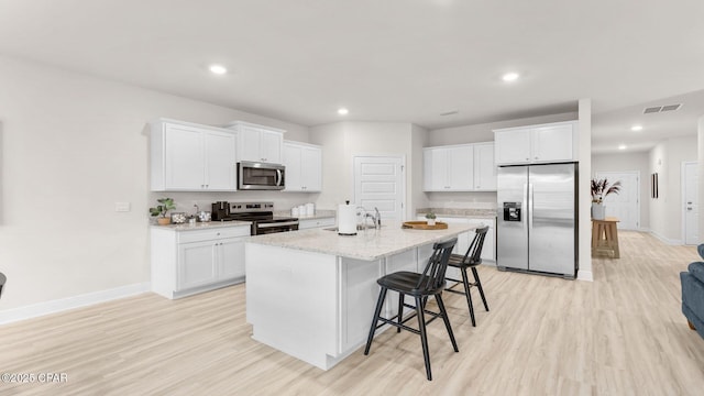 kitchen featuring visible vents, light wood-style flooring, appliances with stainless steel finishes, and white cabinetry