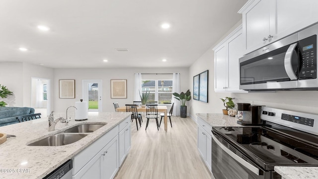 kitchen with visible vents, light wood-style flooring, white cabinets, stainless steel appliances, and a sink