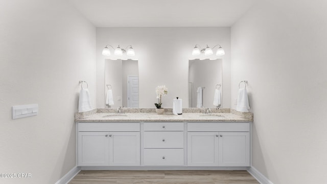 bathroom featuring double vanity, baseboards, and a sink