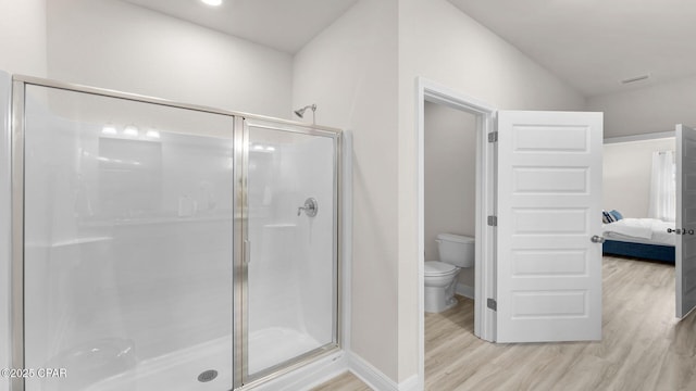 ensuite bathroom with wood finished floors, toilet, ensuite bath, and a shower stall