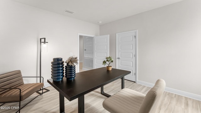 office area with light wood-style flooring, visible vents, and baseboards