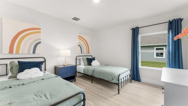 bedroom with baseboards, visible vents, and light wood finished floors