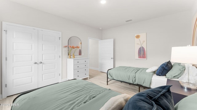 bedroom featuring visible vents, light wood-style floors, a closet, and baseboards