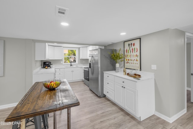 kitchen featuring baseboards, visible vents, stainless steel appliances, light countertops, and white cabinets