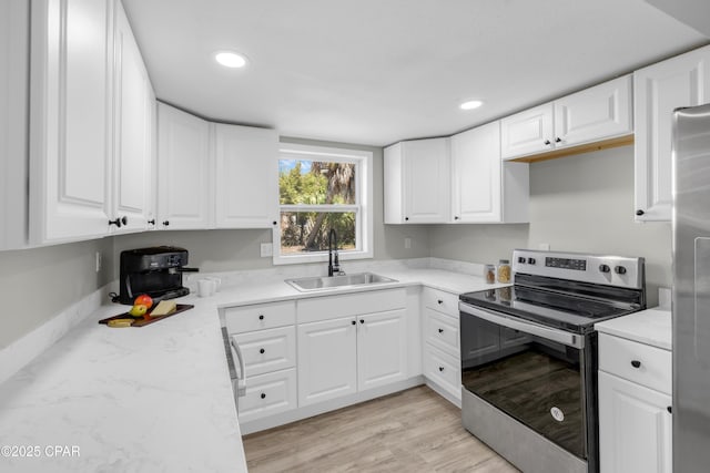 kitchen featuring recessed lighting, a sink, stainless steel appliances, white cabinetry, and light wood-type flooring