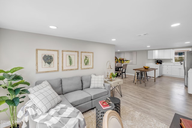 living area with recessed lighting, visible vents, and light wood finished floors