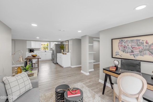 living area featuring recessed lighting, baseboards, and light wood finished floors